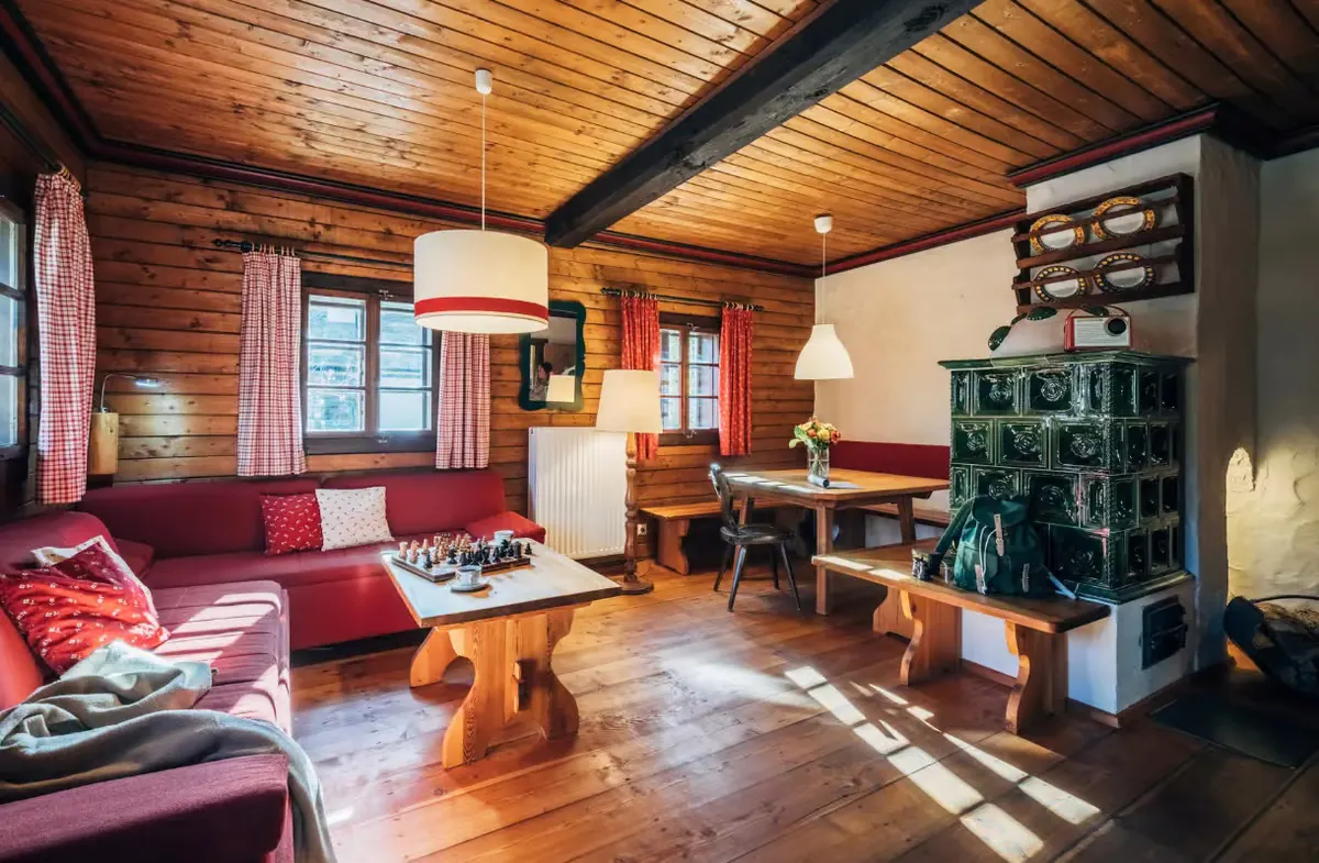 Stube mit Kachelofen, roter Eckbank und Esstisch in der Kolmnock-Wohnung