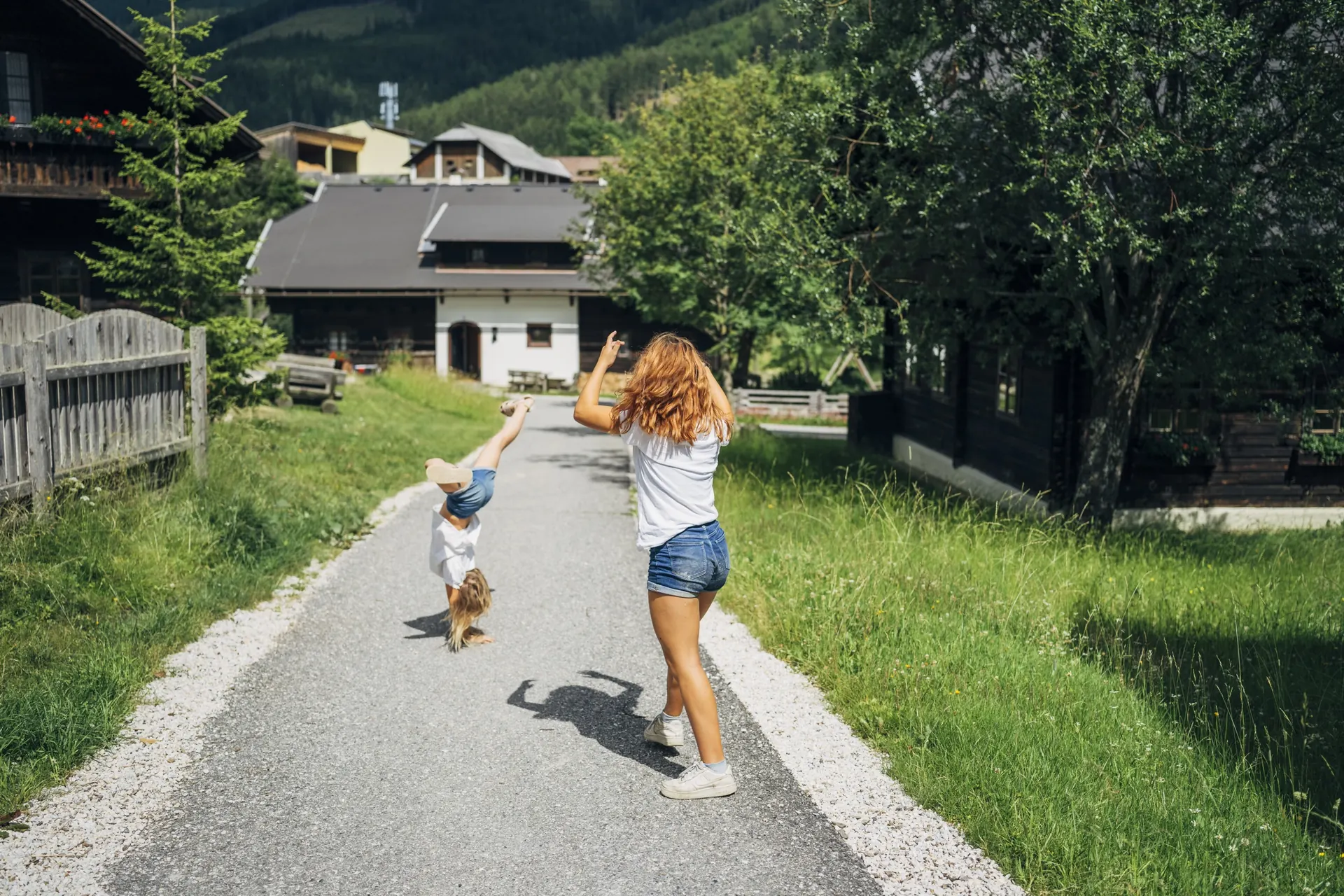 Mutter und Kind laufen mit Hund den Weg durchs Dorf