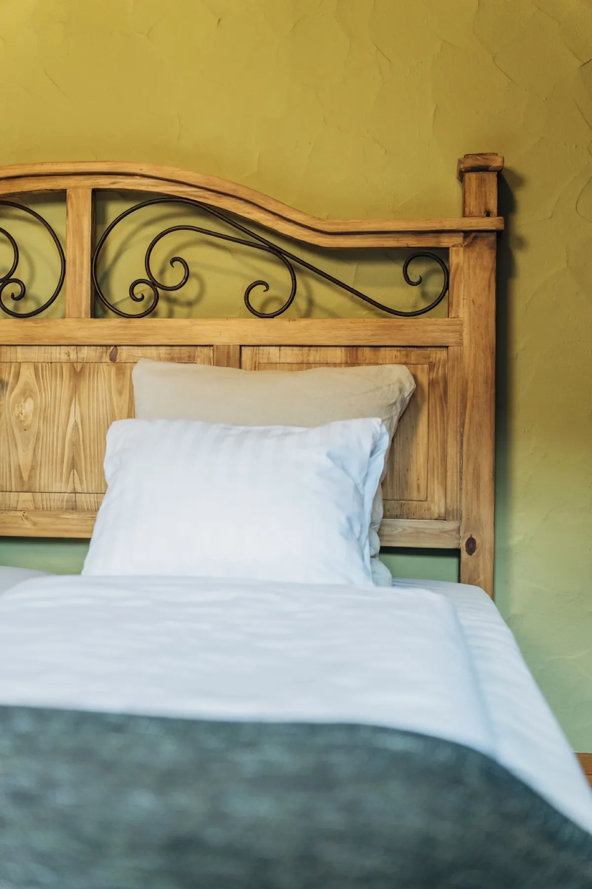 Bett mit weißer Wäsche vor grüner Wand