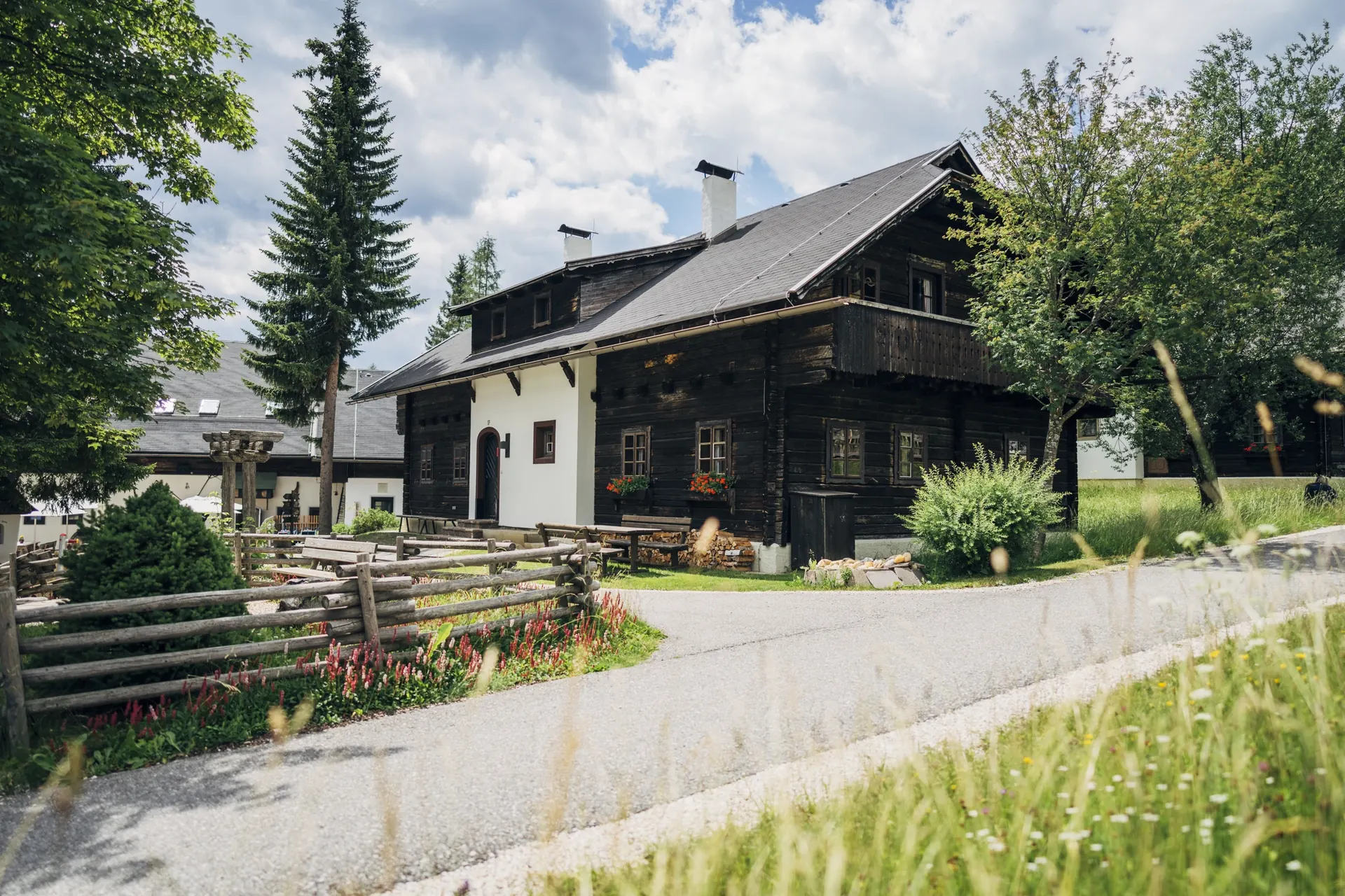Holzhaus mit Zaun und Blumenwiese