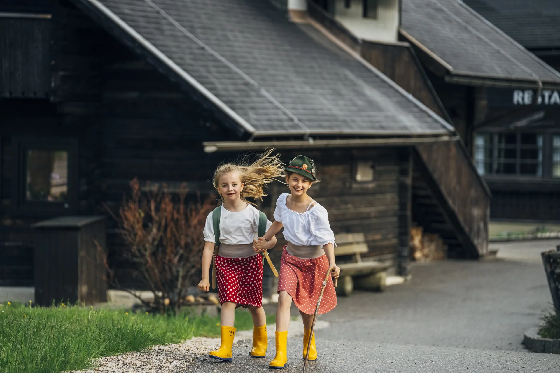 Zwei Kinder laufen zwischen den Holzhäusern