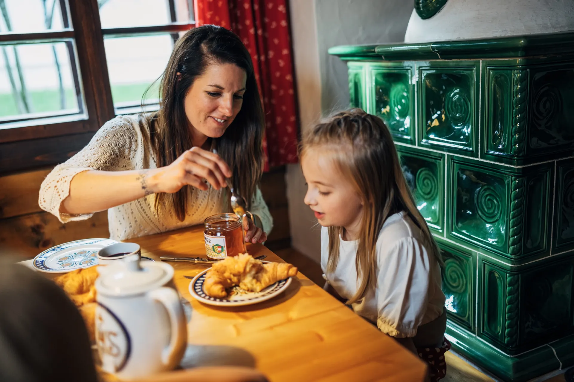 Mutter und Tochter beim Frühstück am Kachelofen