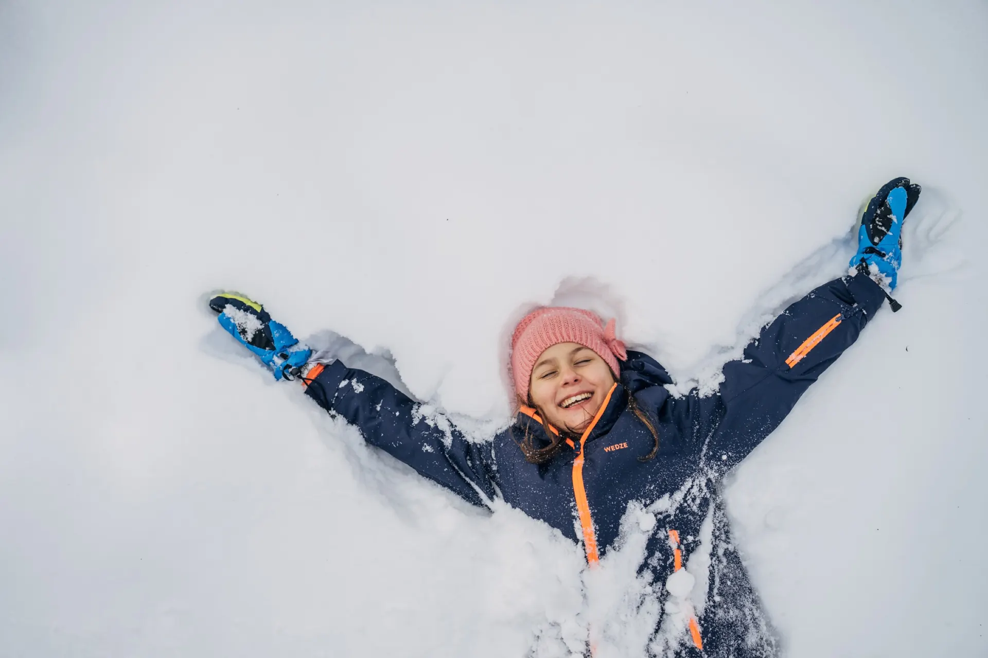 Kind liegt lachend im Schnee