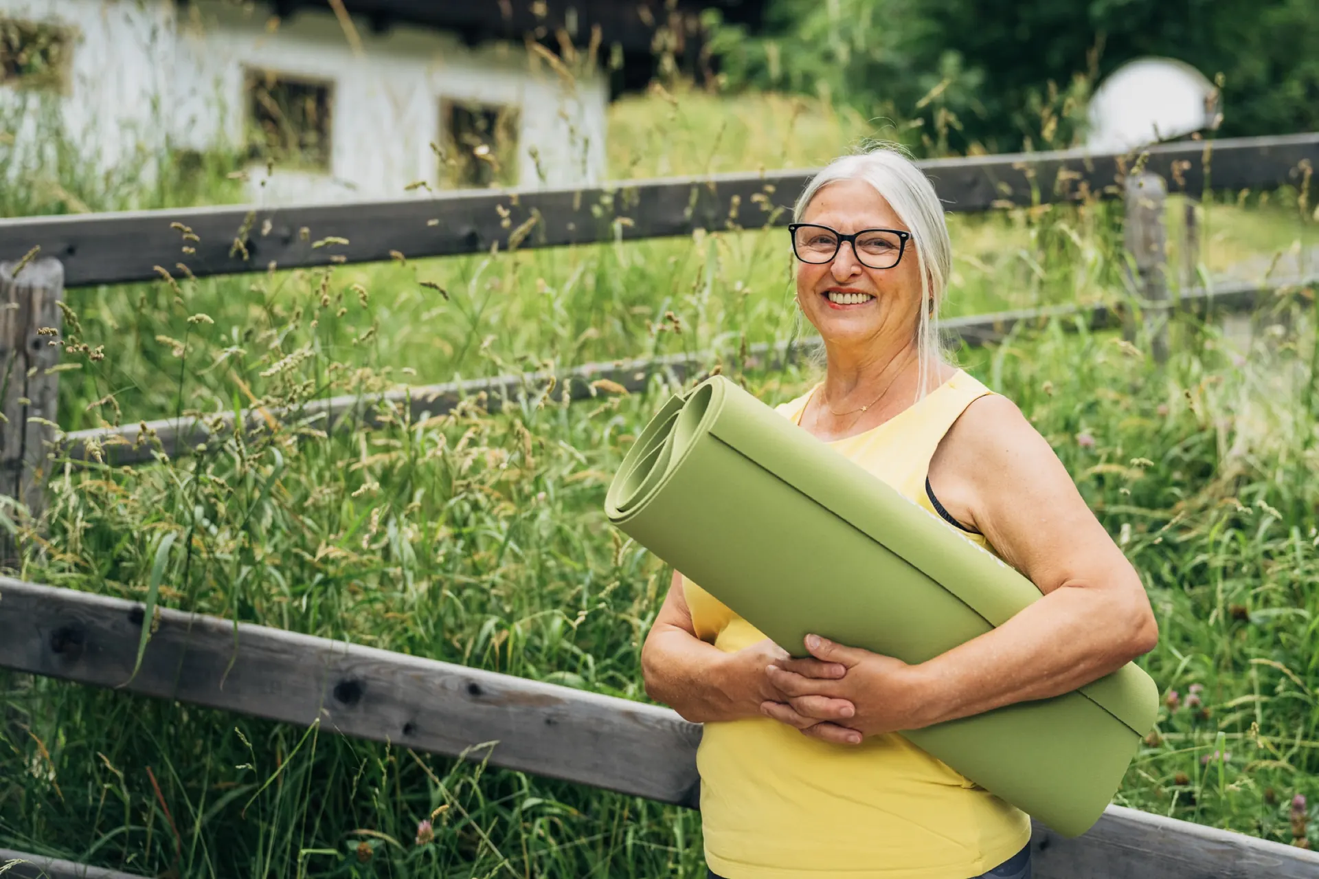 Frau mit Yogamatte am Zaun
