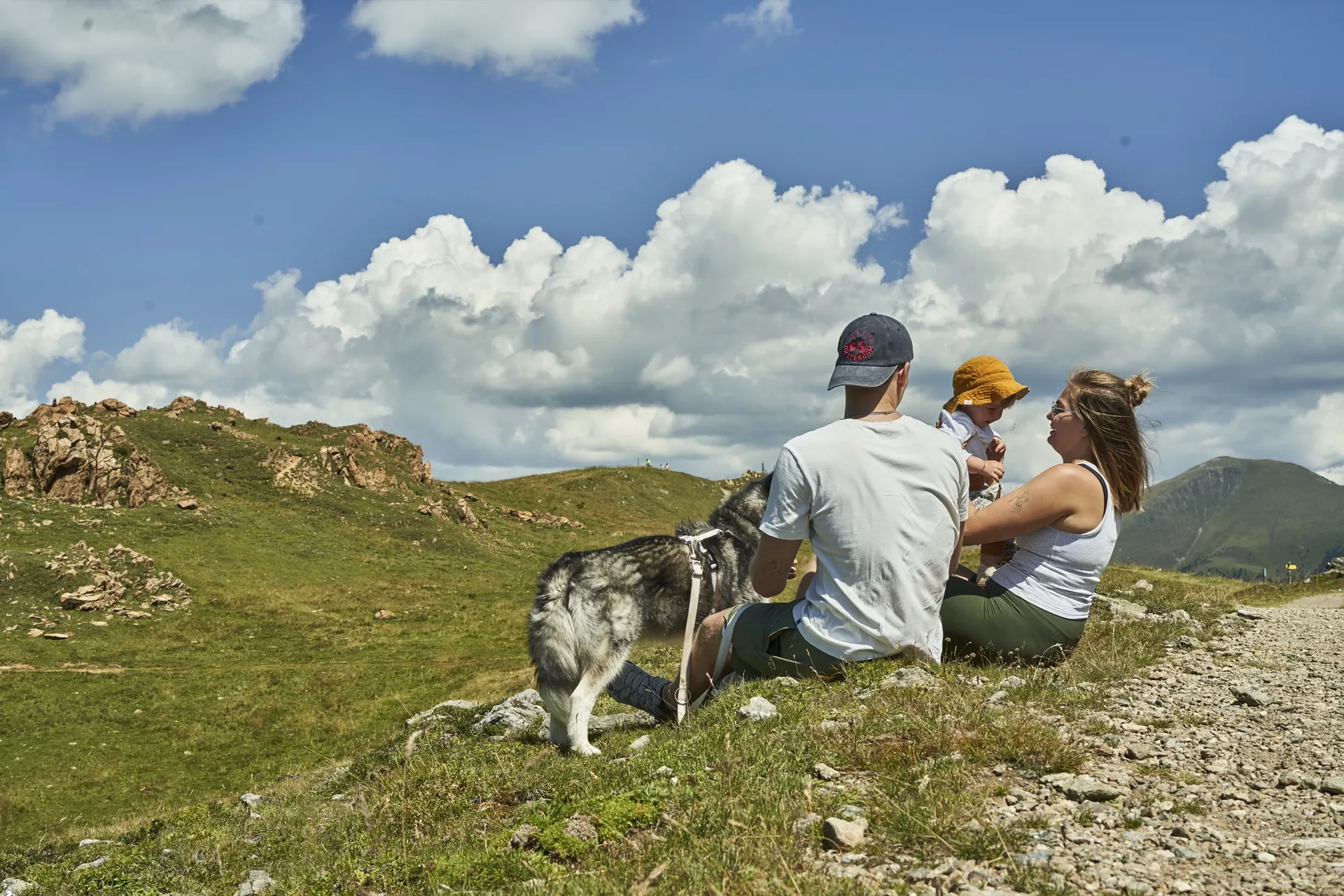 Familie sitzt am Weg mit Blick auf die Berge