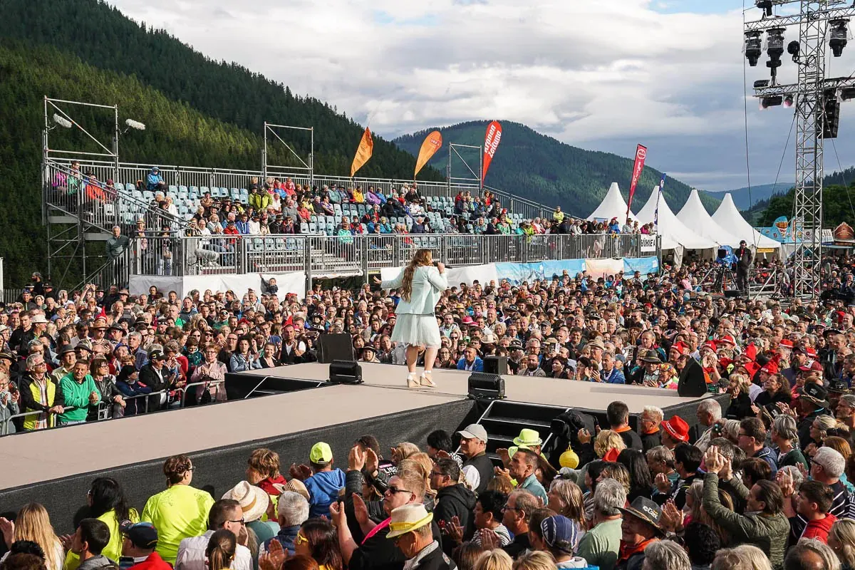 Sängerin auf der Open-Air-Bühne vor voller Tribüne, dahinter die Nockberge