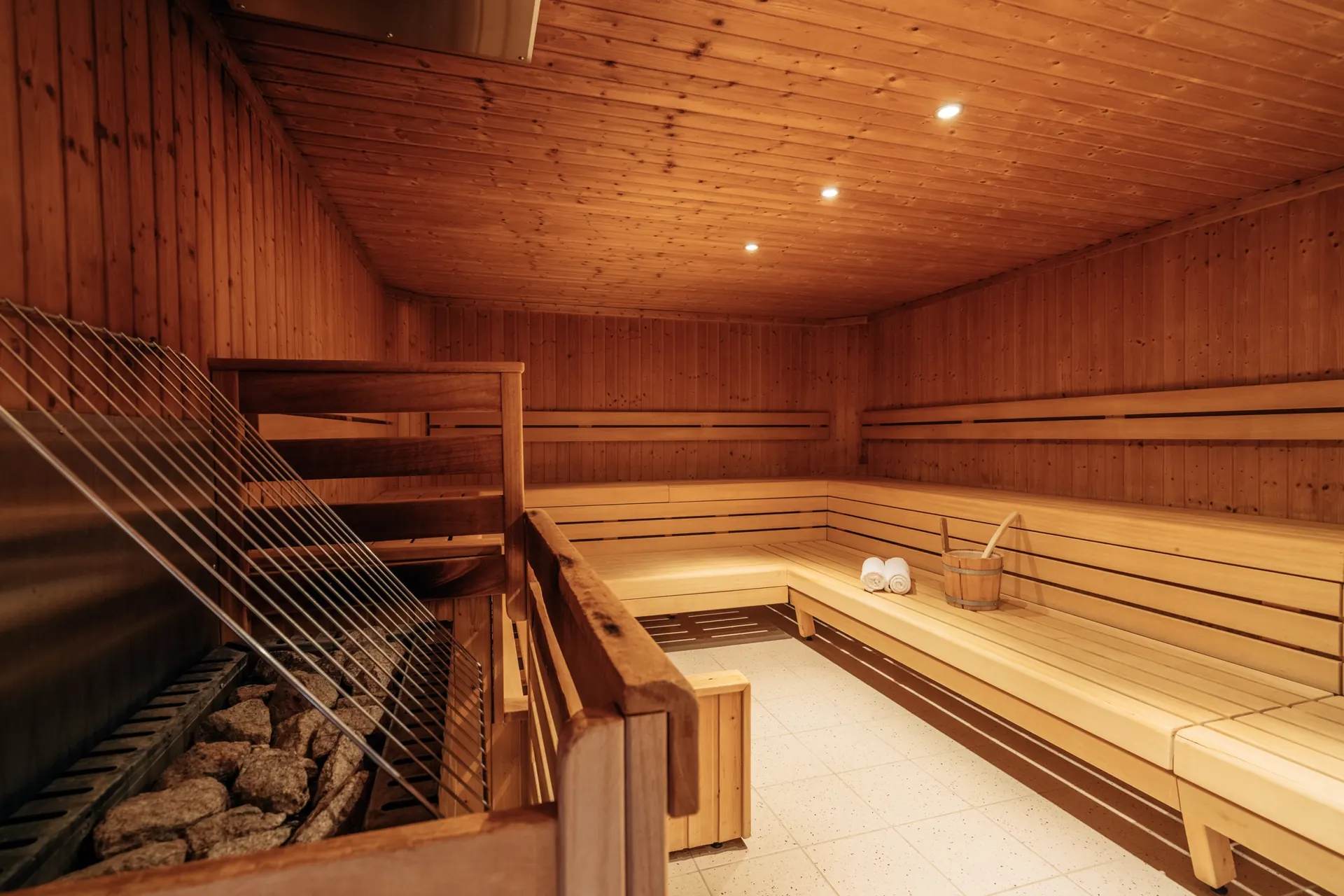 Holzsauna mit Bänken, Steinen und warmem Licht