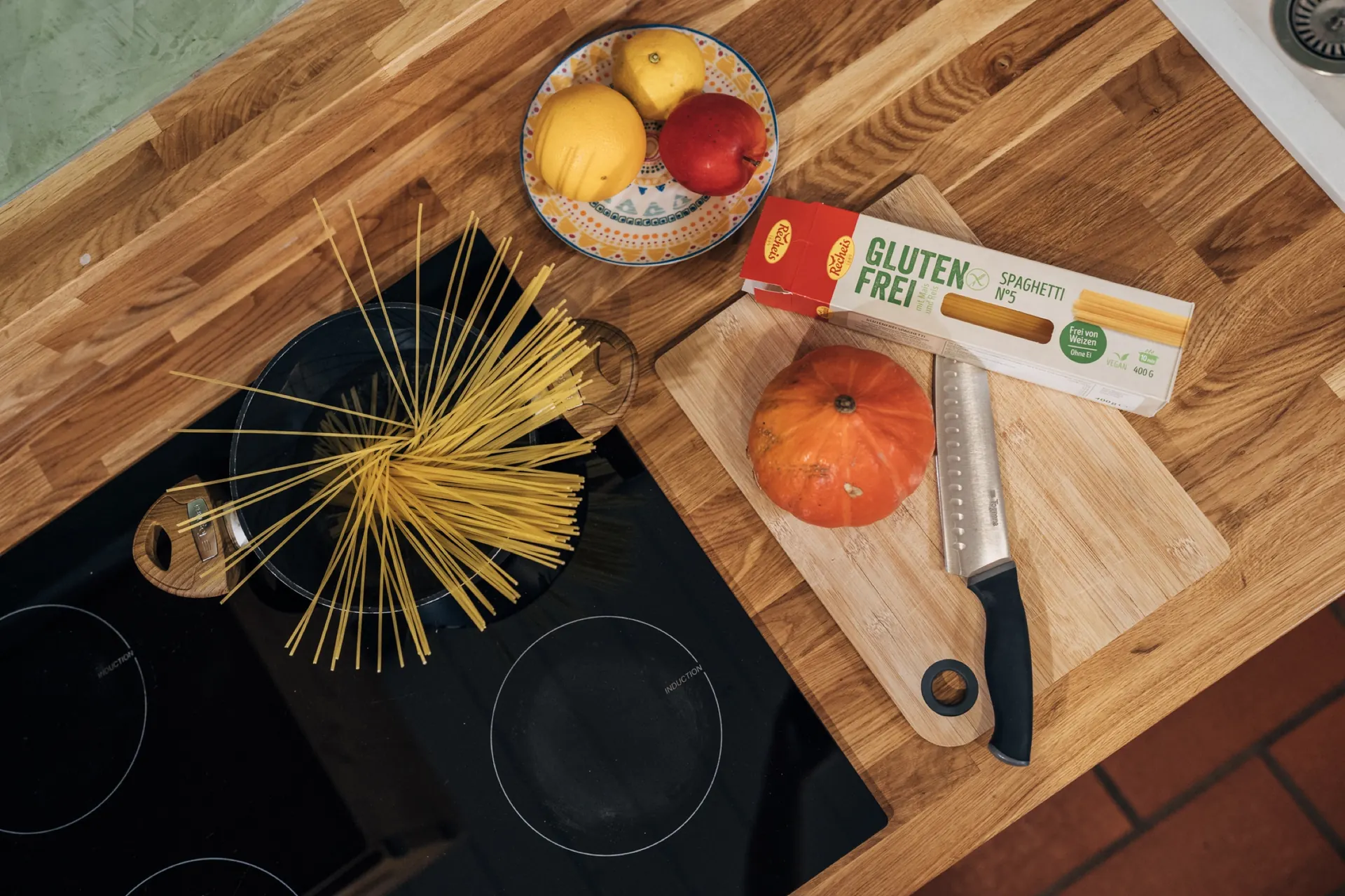 Zutaten auf der Arbeitsfläche: Spaghetti, Kürbis, Obst