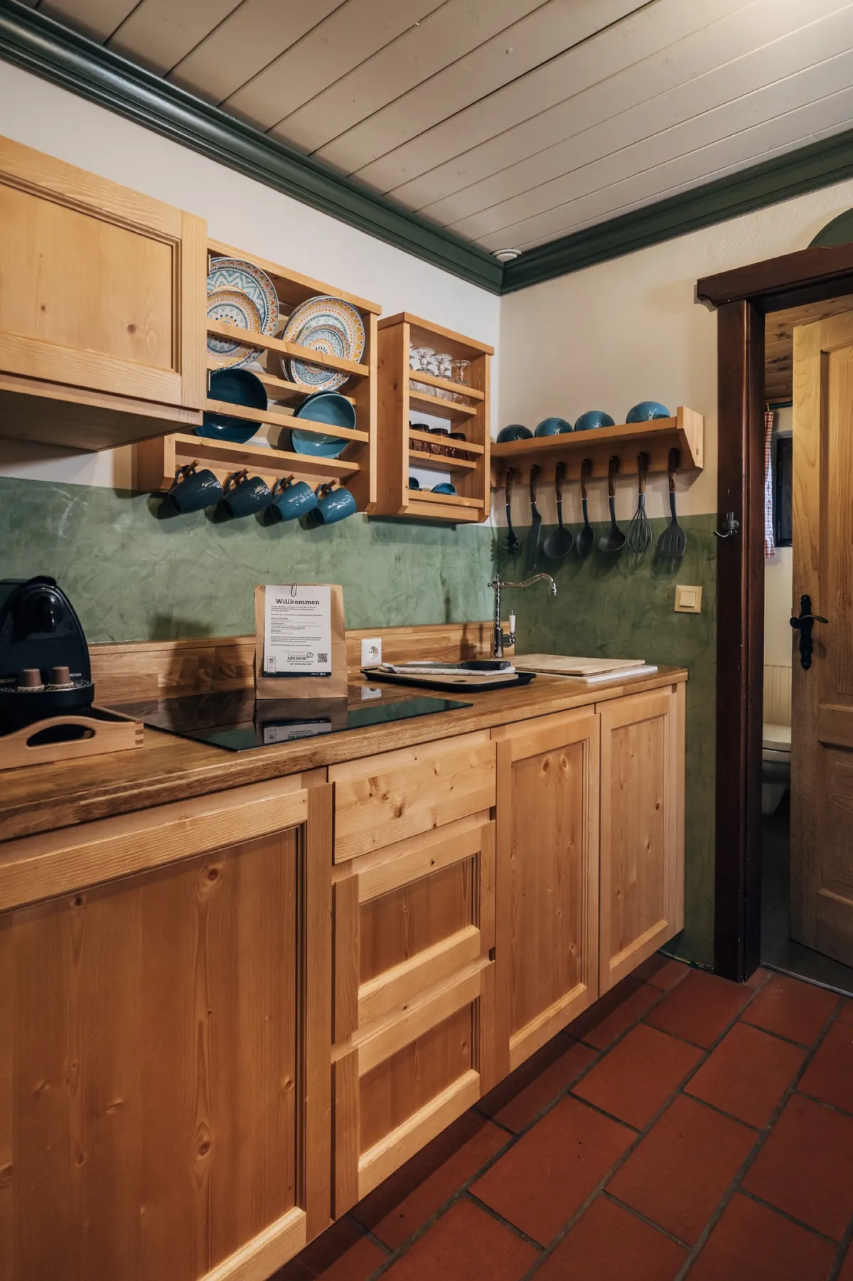 Küche mit Holzfronten, Tellerregal und grüner Wand
