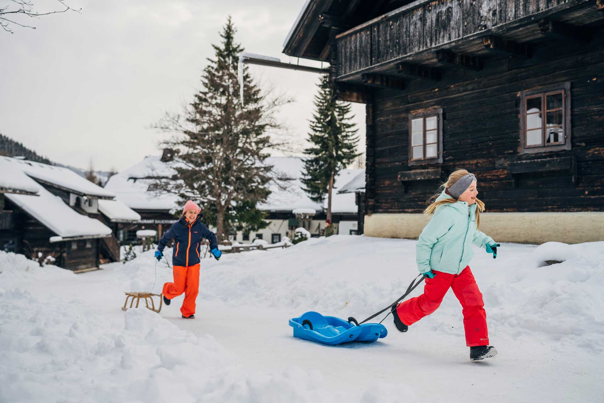 Kinder mit Schlitten im Winterurlaub im autofreien Slow Travel Resort Kirchleitn in Bad Kleinkirchheim, Kärnten