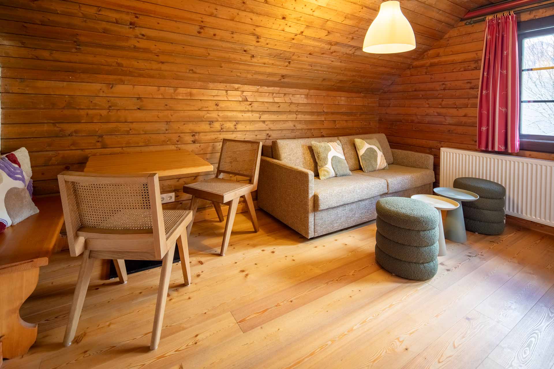 Helle Stube im Appartement Mirnock im Slow Travel Resort Kirchleitn mit Sofa und Essecke für den Familienurlaub.