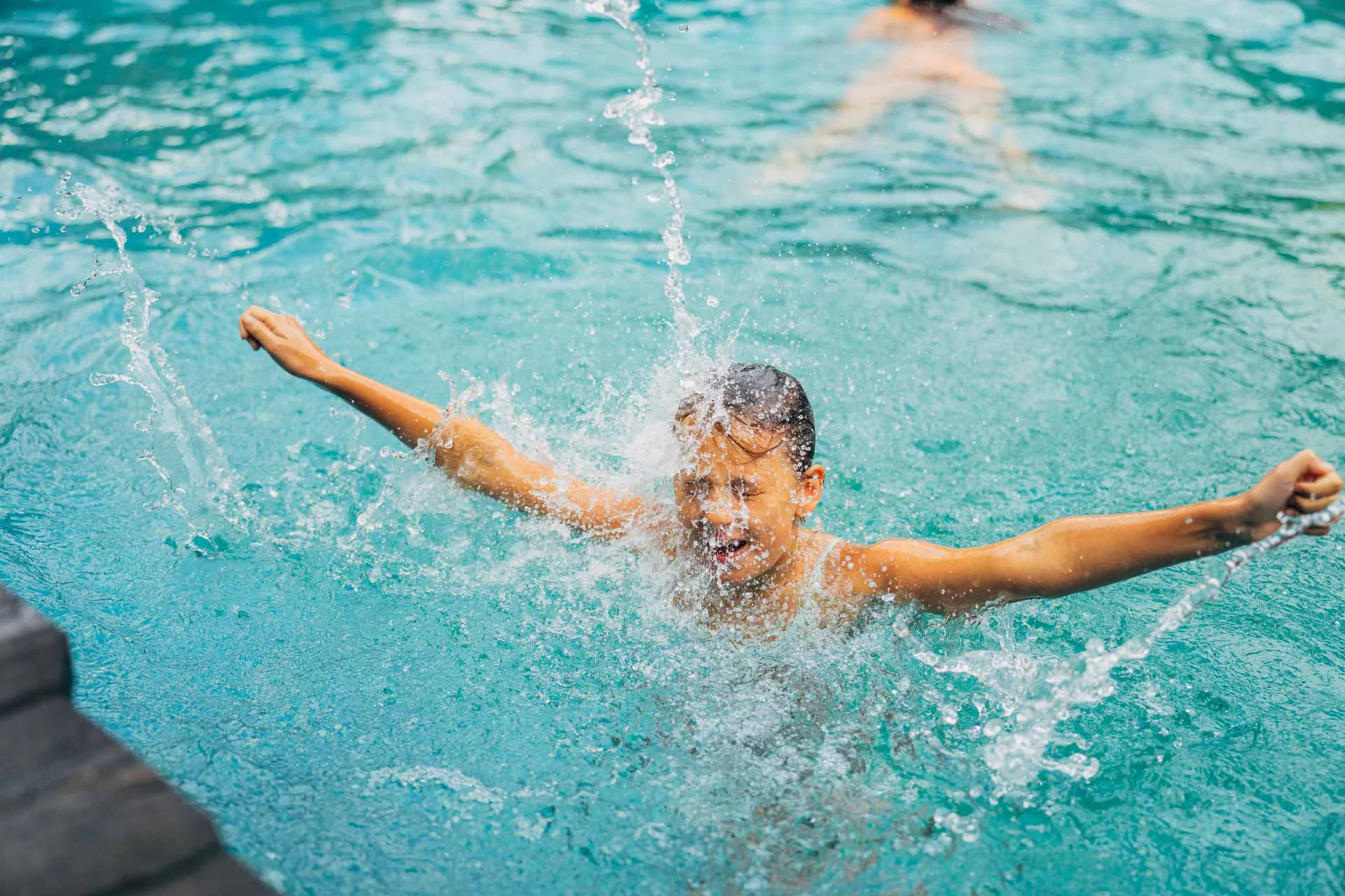 Beim Familien Sommerurlaub Kärnten im Naturbadeteich im Slow Travel Resort Kirchleitn abkühlen. Junge im Wasser beim Baden.
